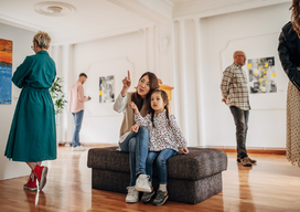 Diverse group of visitors in modern art gallery looking at paintings. Mother brought her daughter.