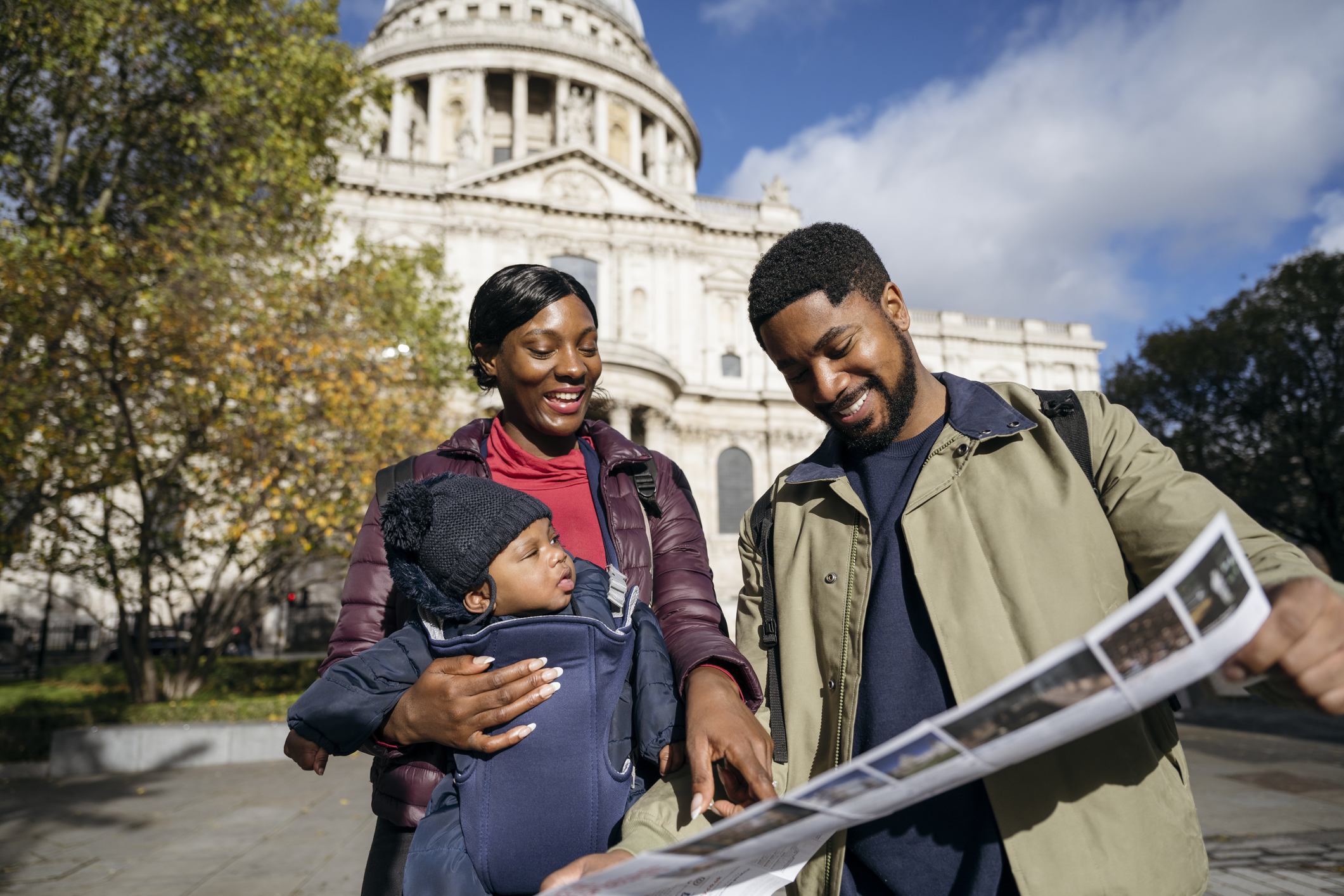Smiling young family looking at London travel brochure