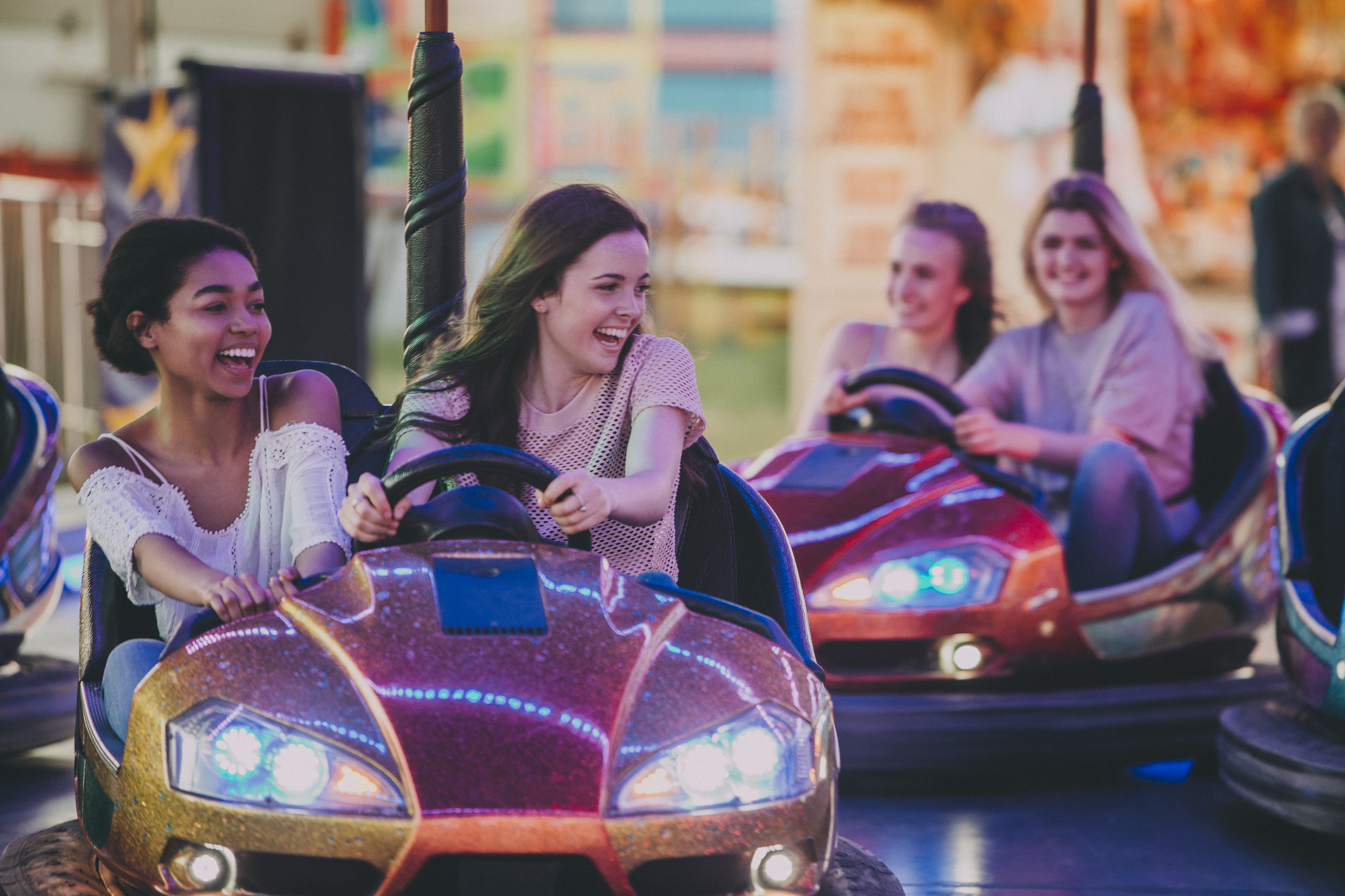 Two young friends driving a bumper car at an amusement park